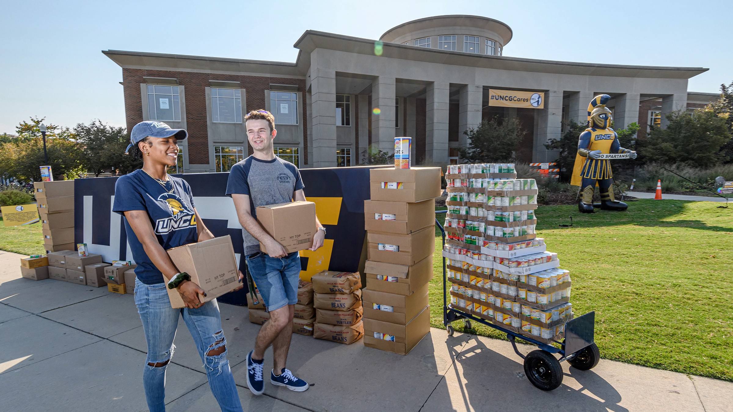 Two UNCG students carrying boxes of food donated to Spartan Open Pantry.